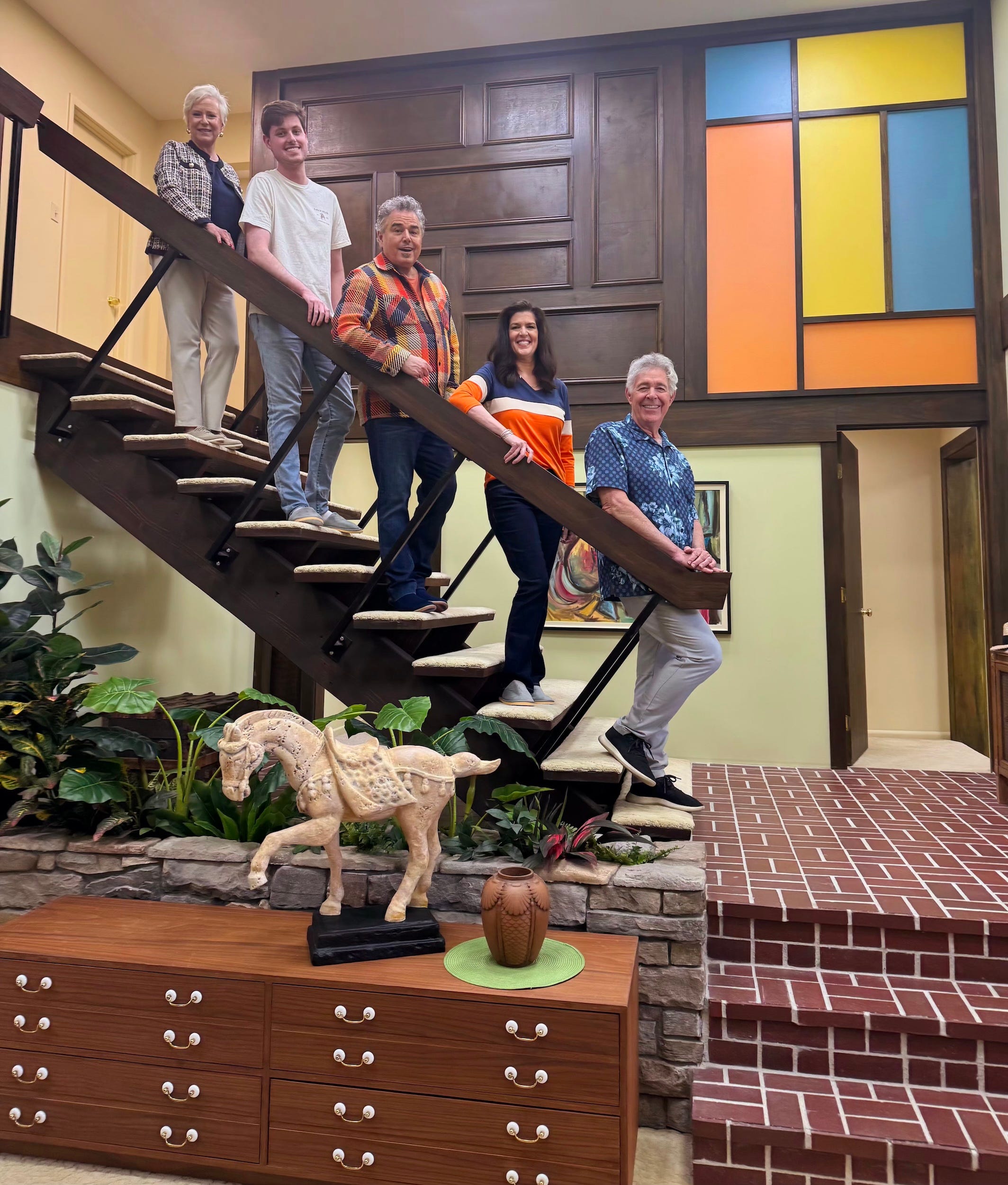 Five people standing on the "Brady Bunch" stairs.