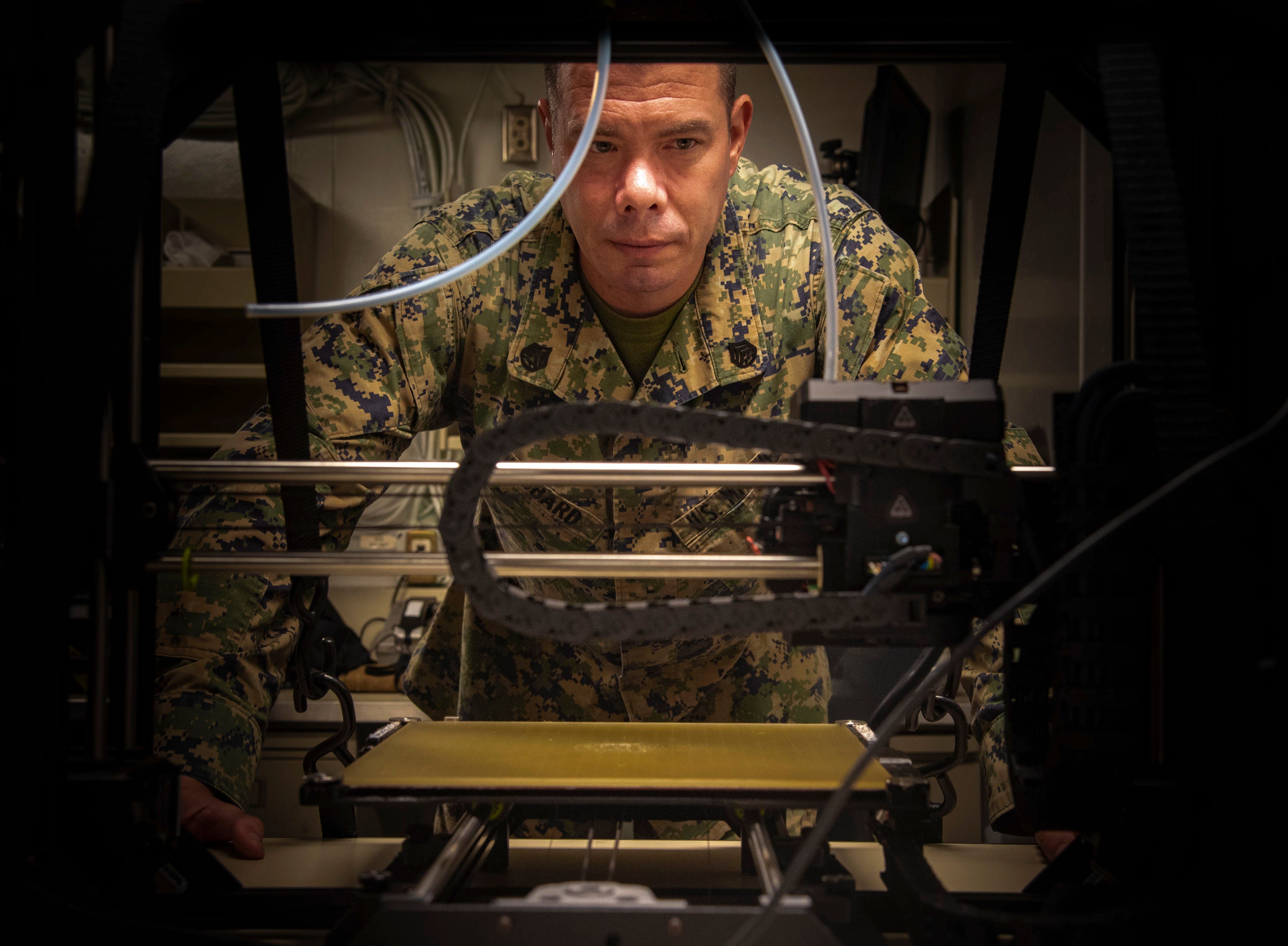 A US Marine watches a 3D printer as it prints an equipment part used aboard USS New Orleans in the Philippine Sea on Aug. 24, 2020.