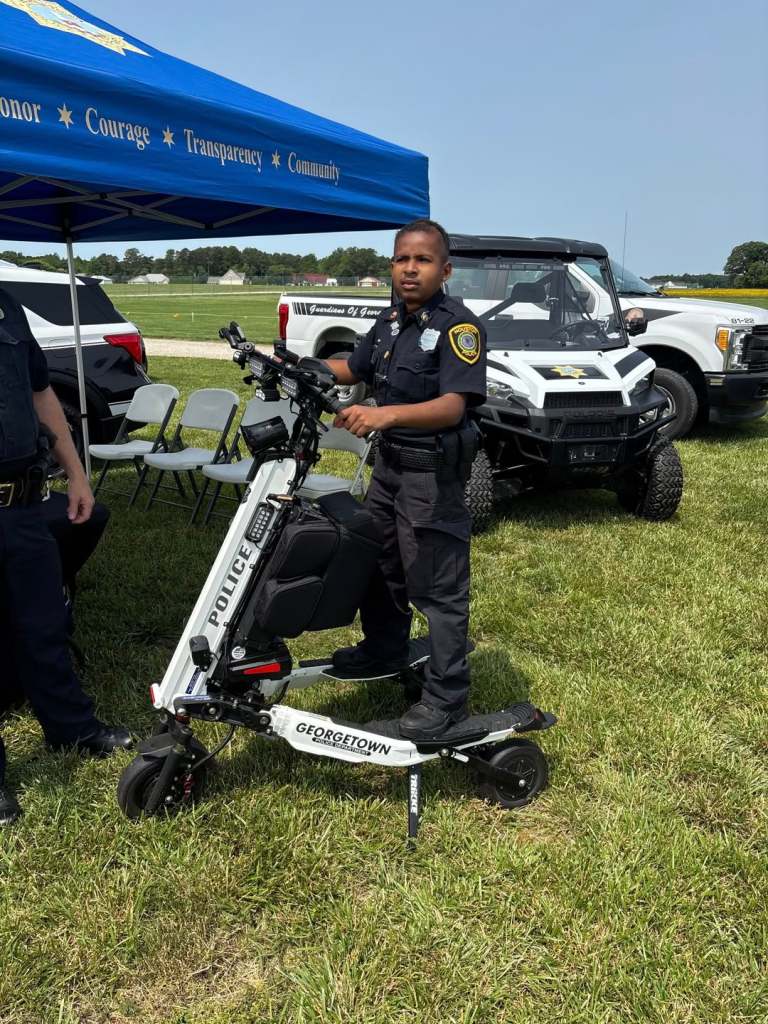 Young police officer standing with police scooter.