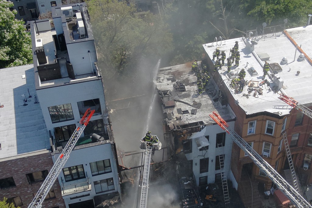 Aerial view of firefighters battling a three-alarm fire at a three-story building.