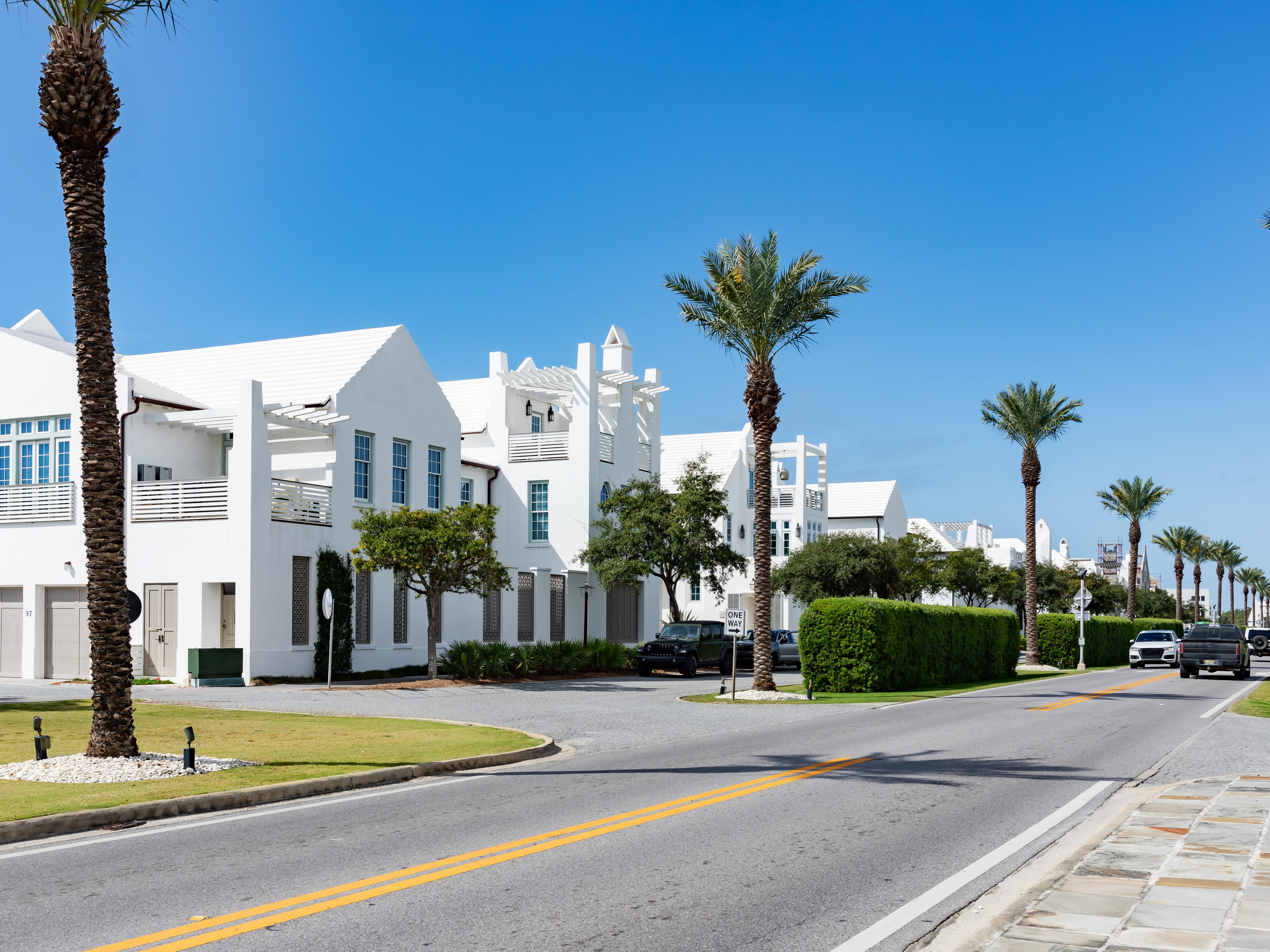 White houses along a palm-tree-lined street.