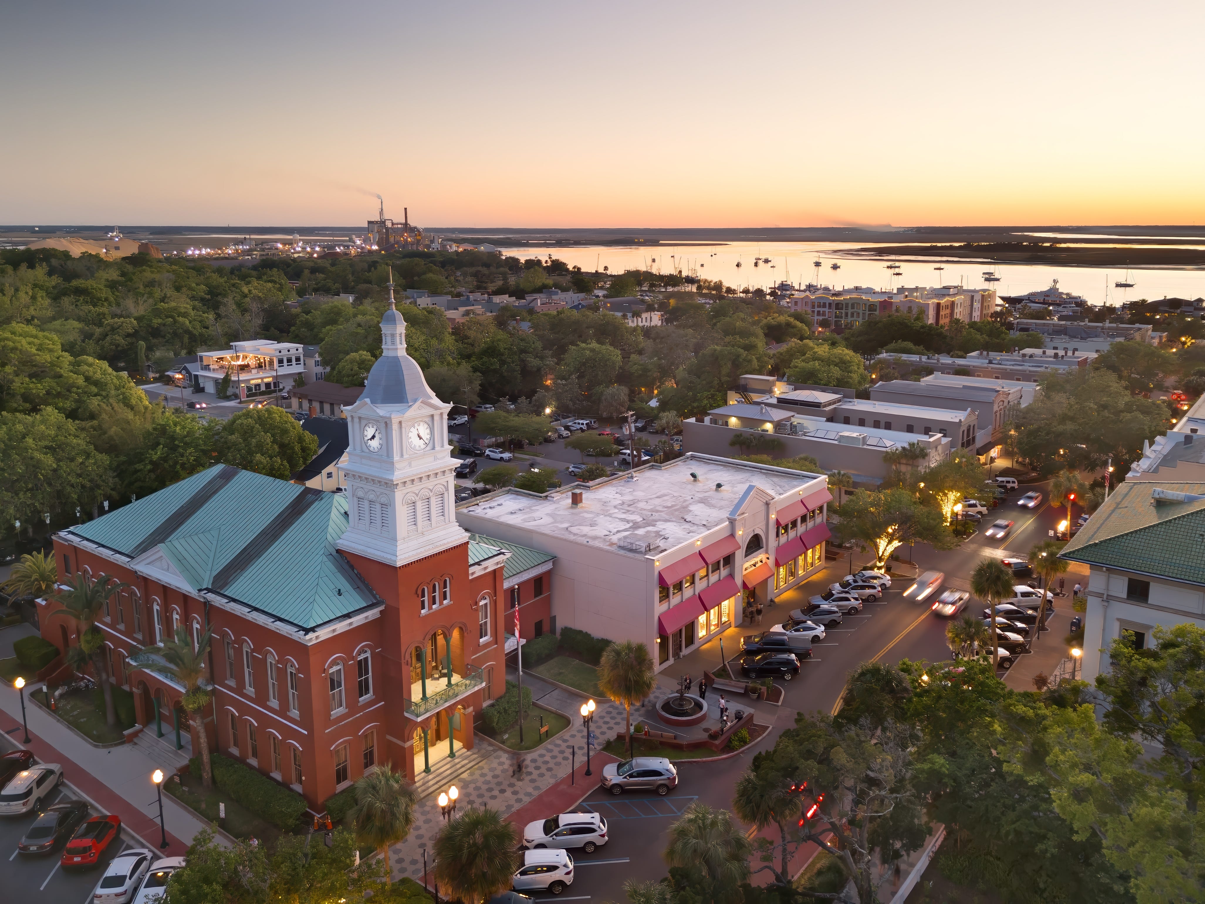 An aerial view of a beach town with a church and shops at sunset.