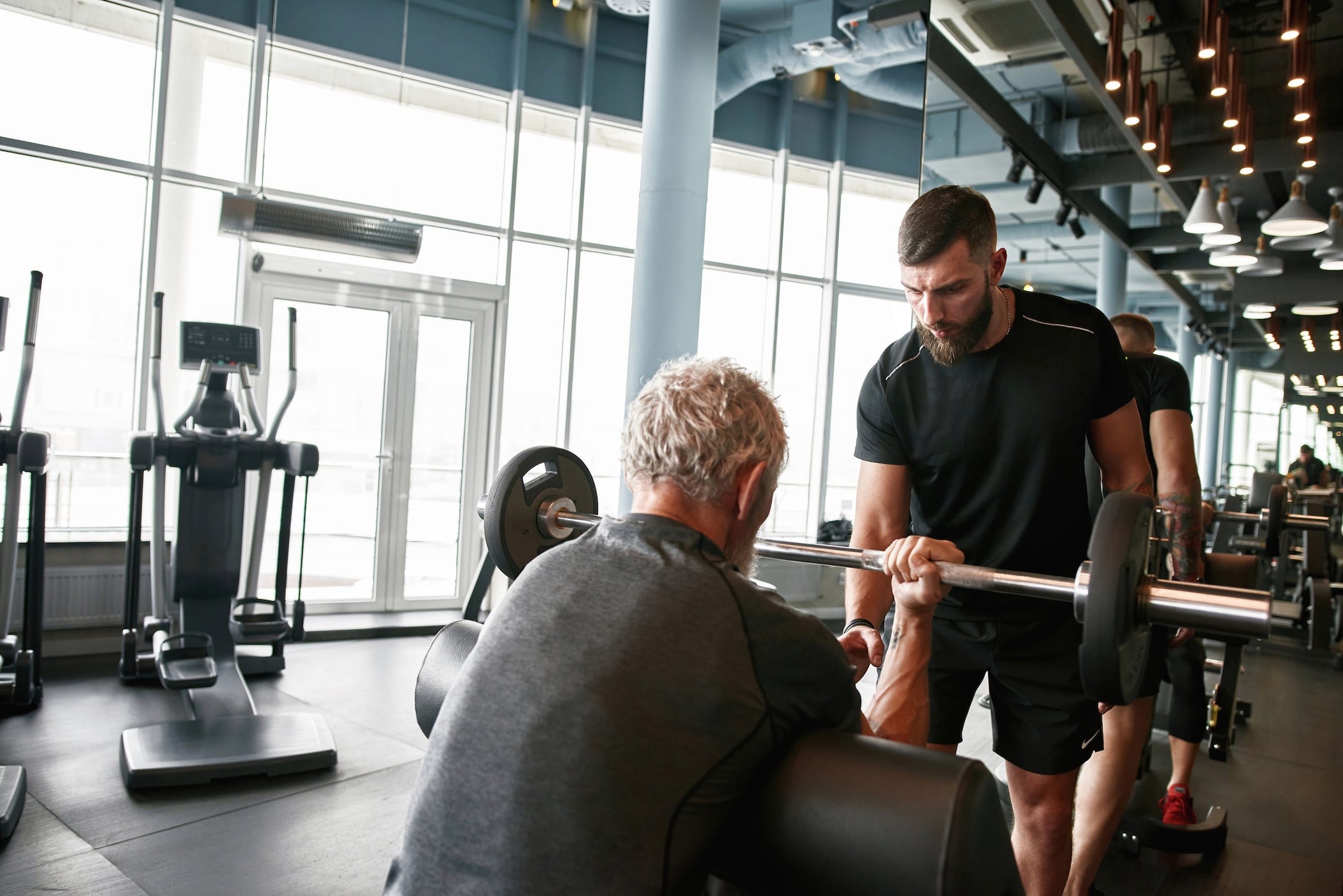 personal trainer helping older man, weightlifting