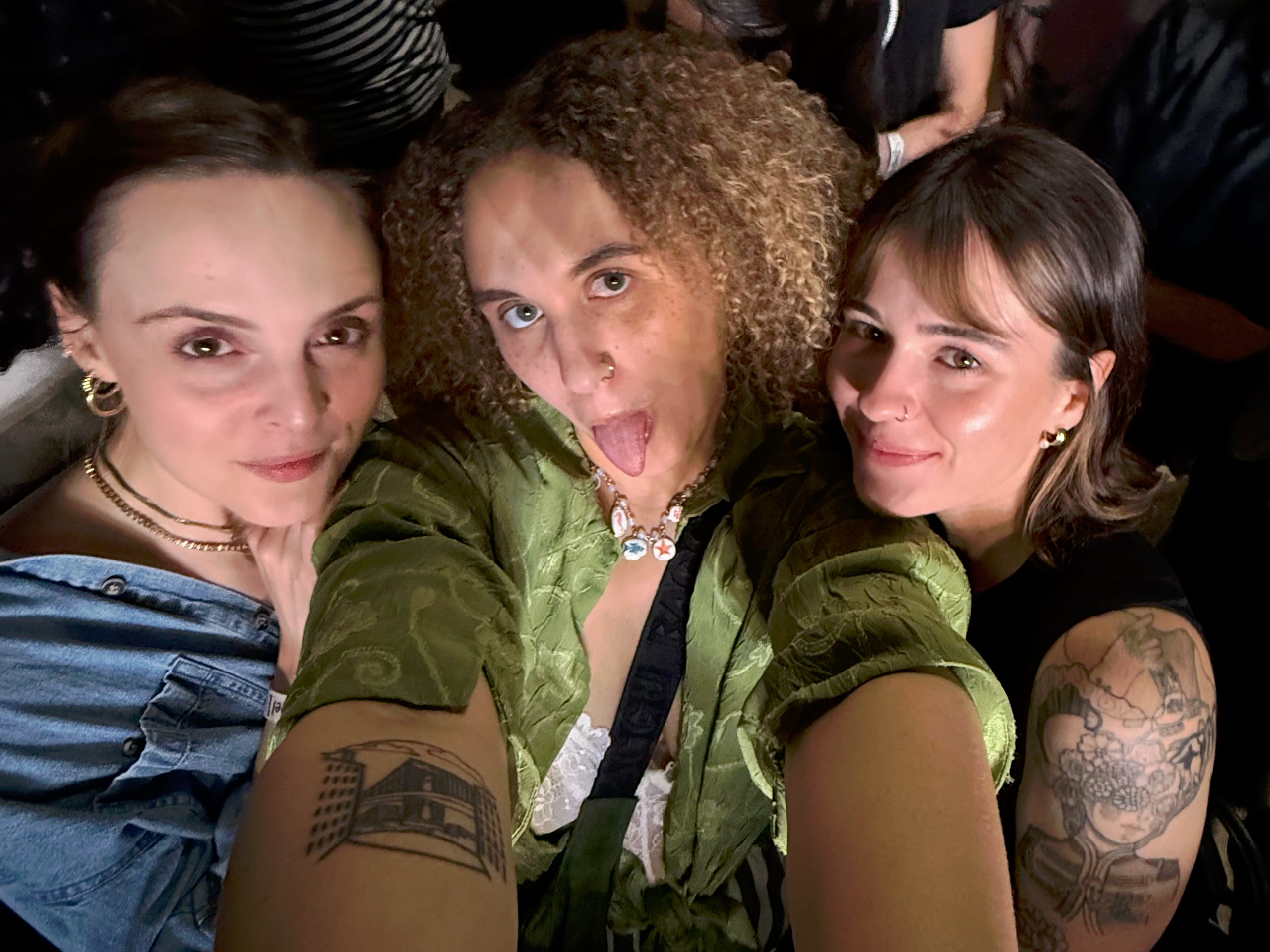 The author (center) sticking her tongue out for a selfie with two friends at a concert.