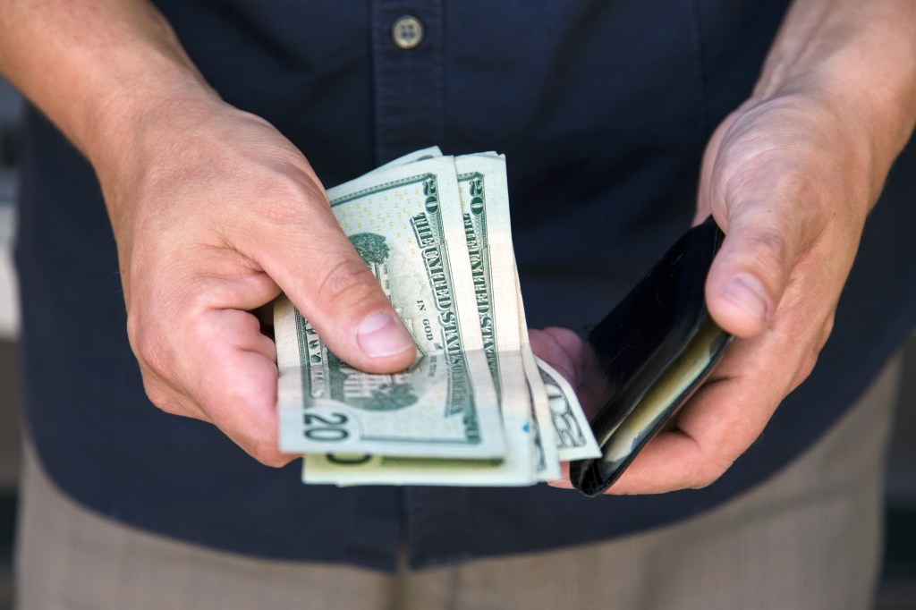 Man putting cash into his wallet.