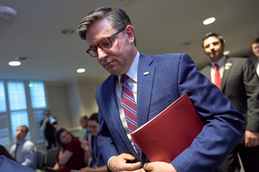 Mike Johnson, Speaker of the House, carrying a red folder.