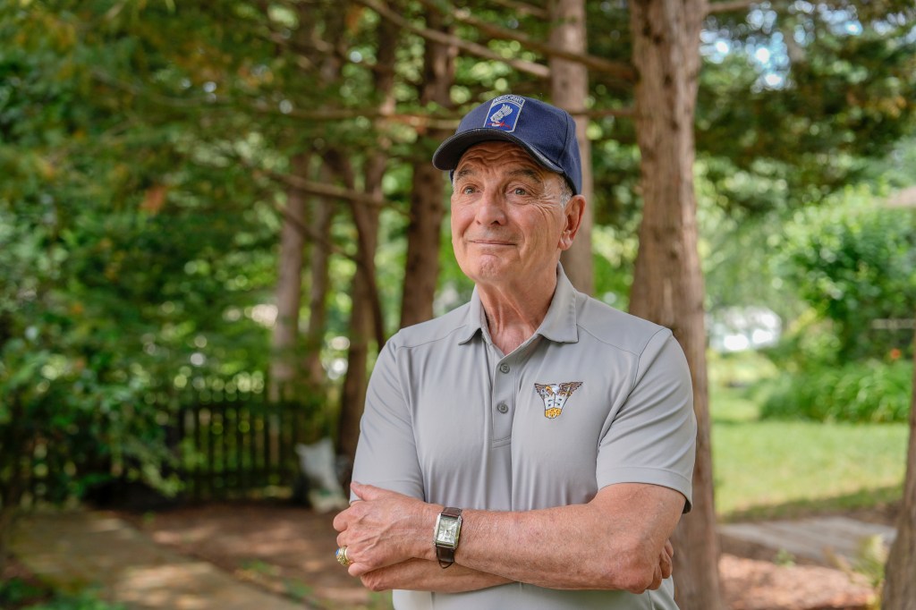 Portrait of a veteran wearing a gray polo shirt and a military-style cap.