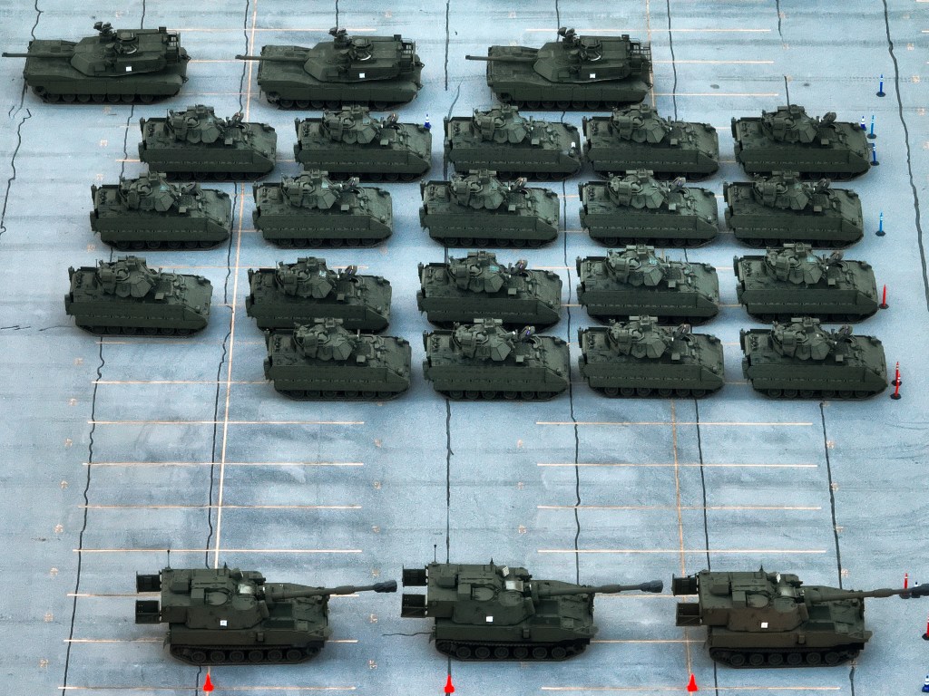 Aerial view of military vehicles lined up in a parking lot.