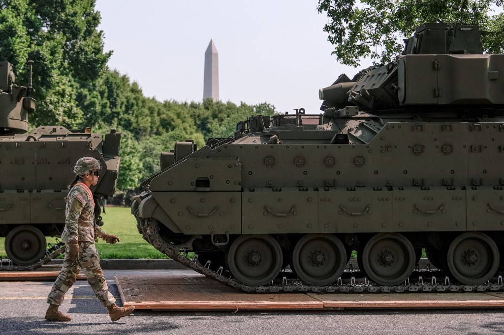 A U.S. Army soldier walks past Bradley fighting vehicle staged in West Potomac Park ahead of an upcoming military parade.