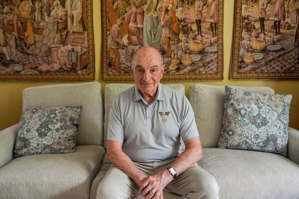 Portrait of a smiling older man sitting on a couch.