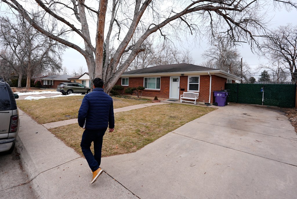 A man walks past a brick house where cremated remains were found.