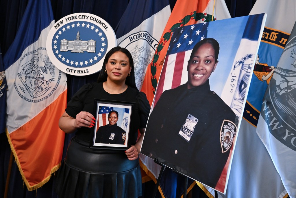 Genesis Villella holding photos of her mother, late NYPD Detective Miosotis Familia, at a City Hall presser regarding a HOME RULE bill.