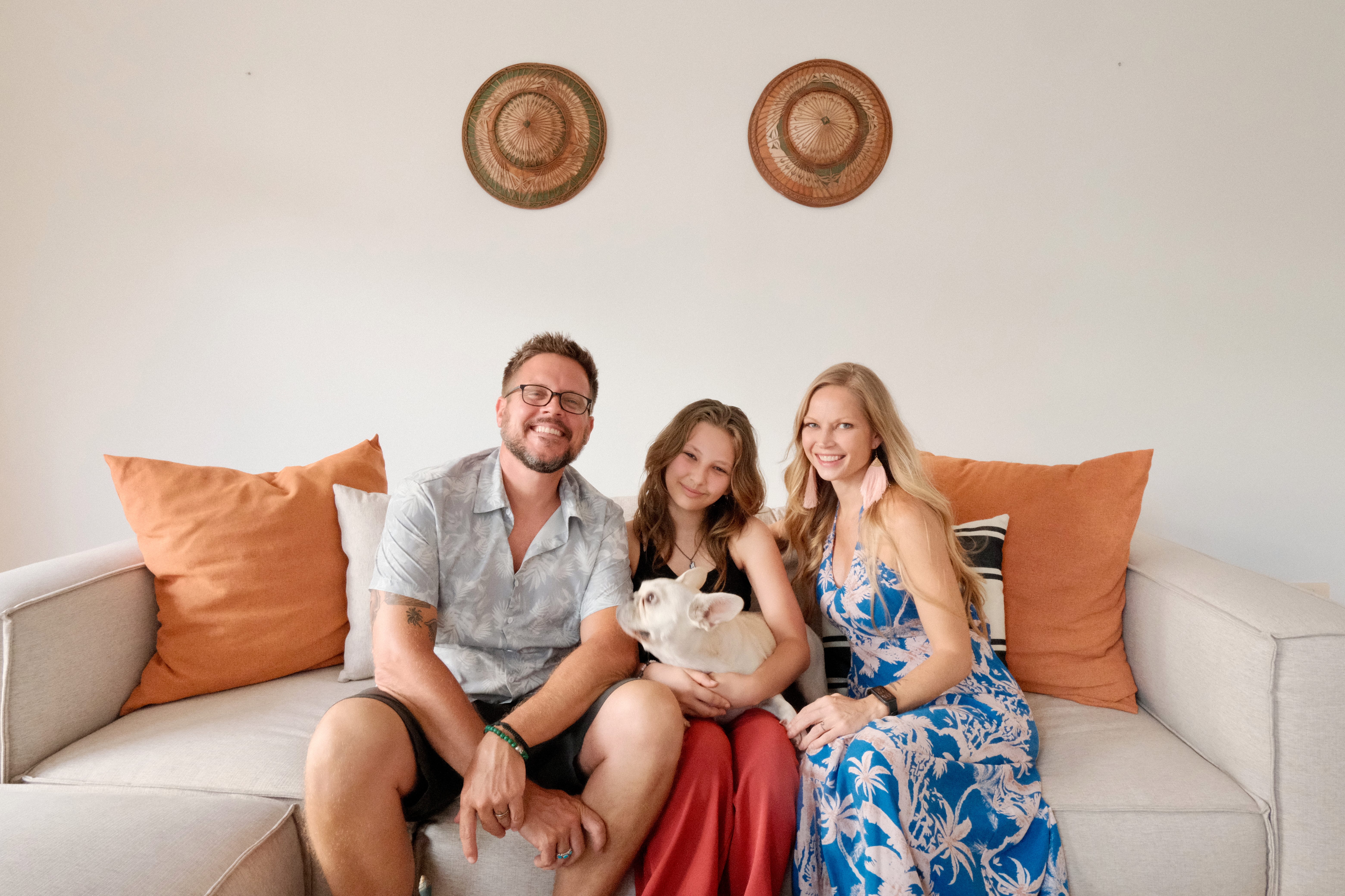 A family of three posing with their dog on their sofa in their villa in Koh Samui, Thailand.