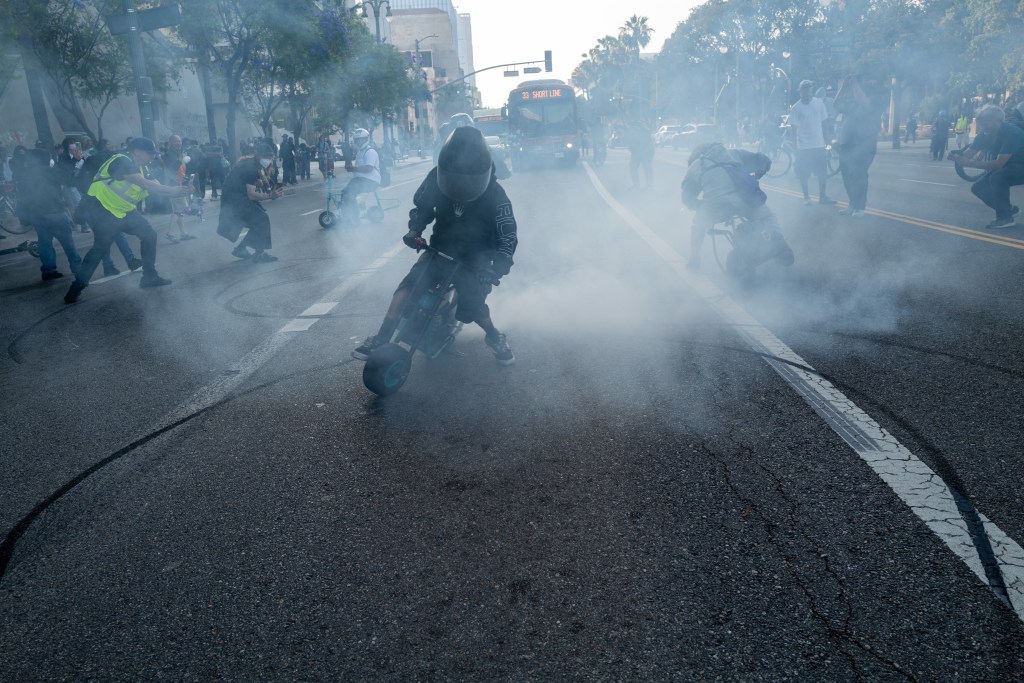 Protestors riding motorcycles and creating smoke in the street.
