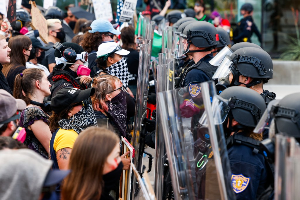 Protesters face off against police in riot gear during a demonstration against ICE immigration raids.