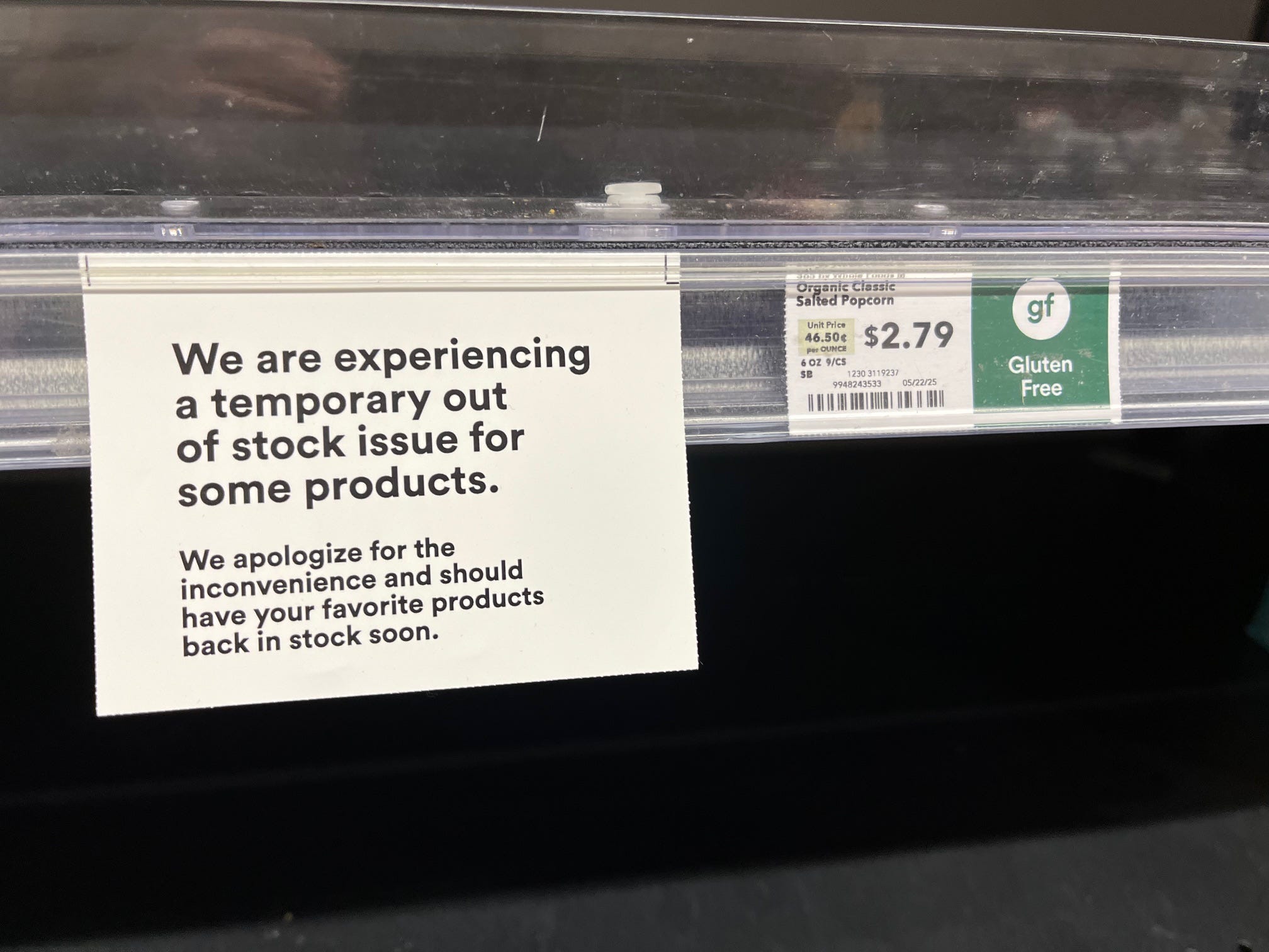 A tag on a shelf in the snack aisle at a Whole Foods store reads: "We are experiencing a temporary out of stock issue for some products. We apologize for the inconvenience and should have your favorite products back in stock soon."