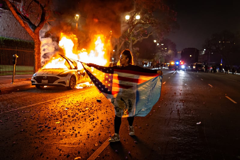 A car burns on East 3rd street after protesters set a car on fire as demonstrators clashed authorities in downtown Los Angeles due to the immigration raids in the city.