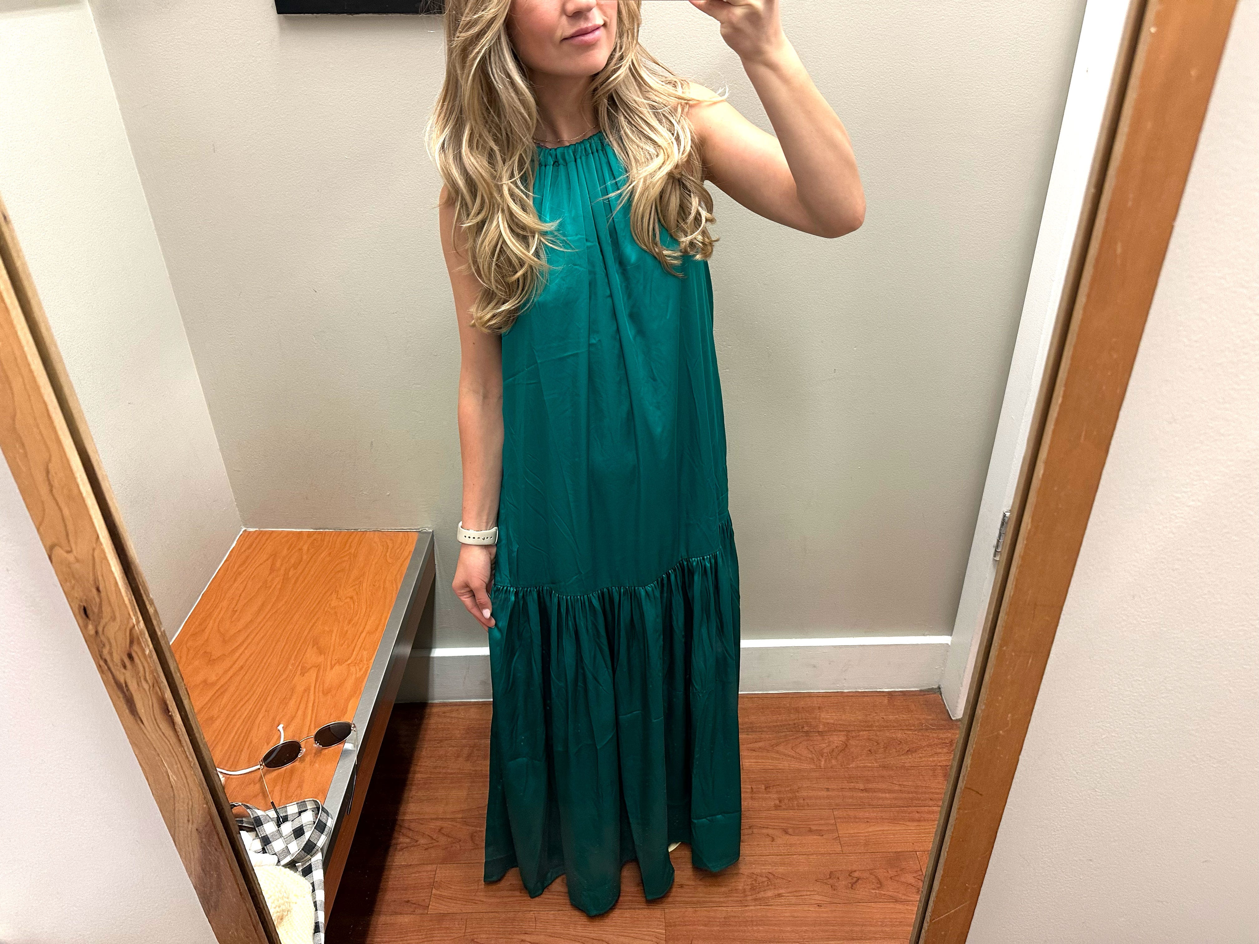 Chloe wears a green halter dress in a fitting room.