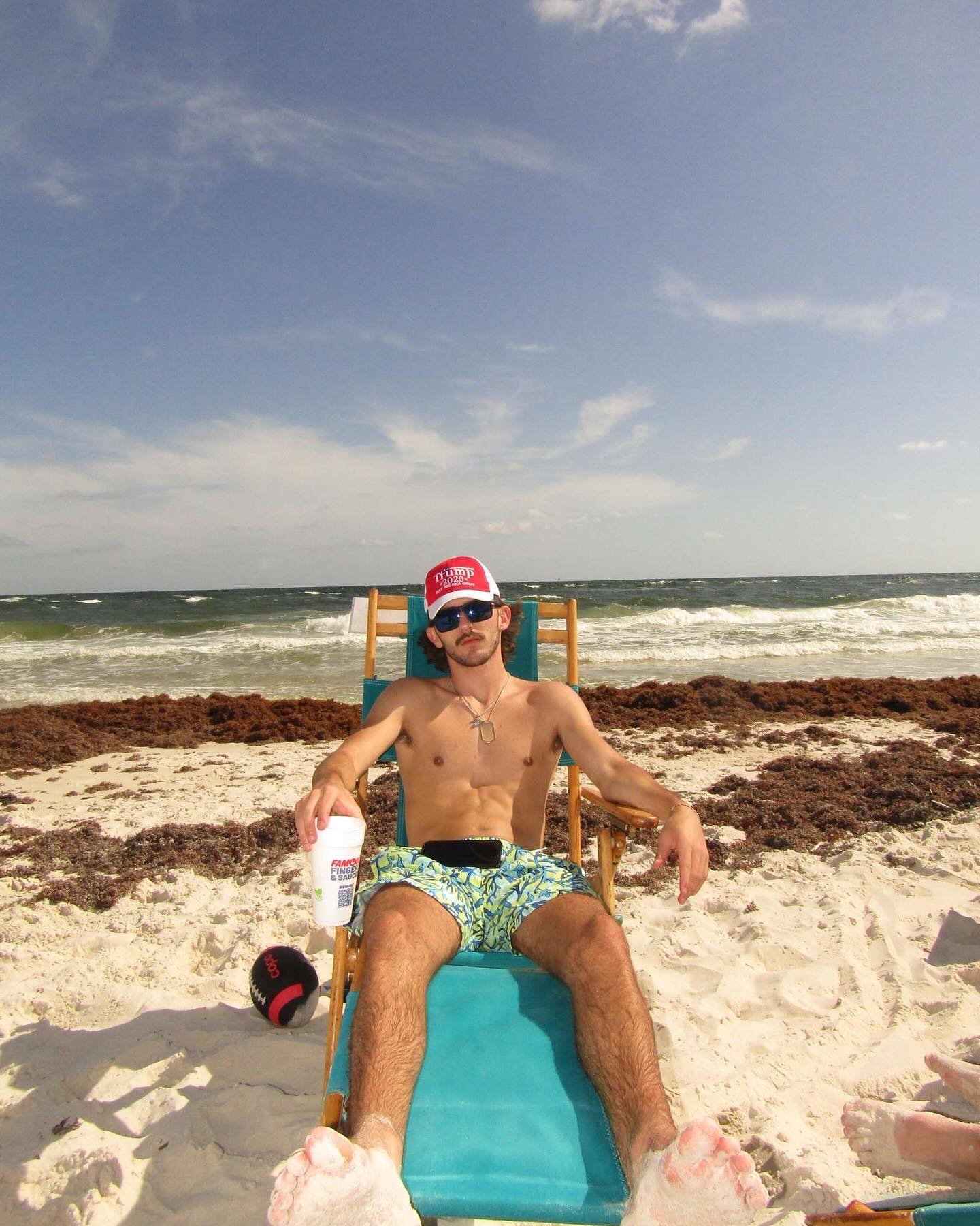 Grayson Chrisley sits on the beach in a chair. 