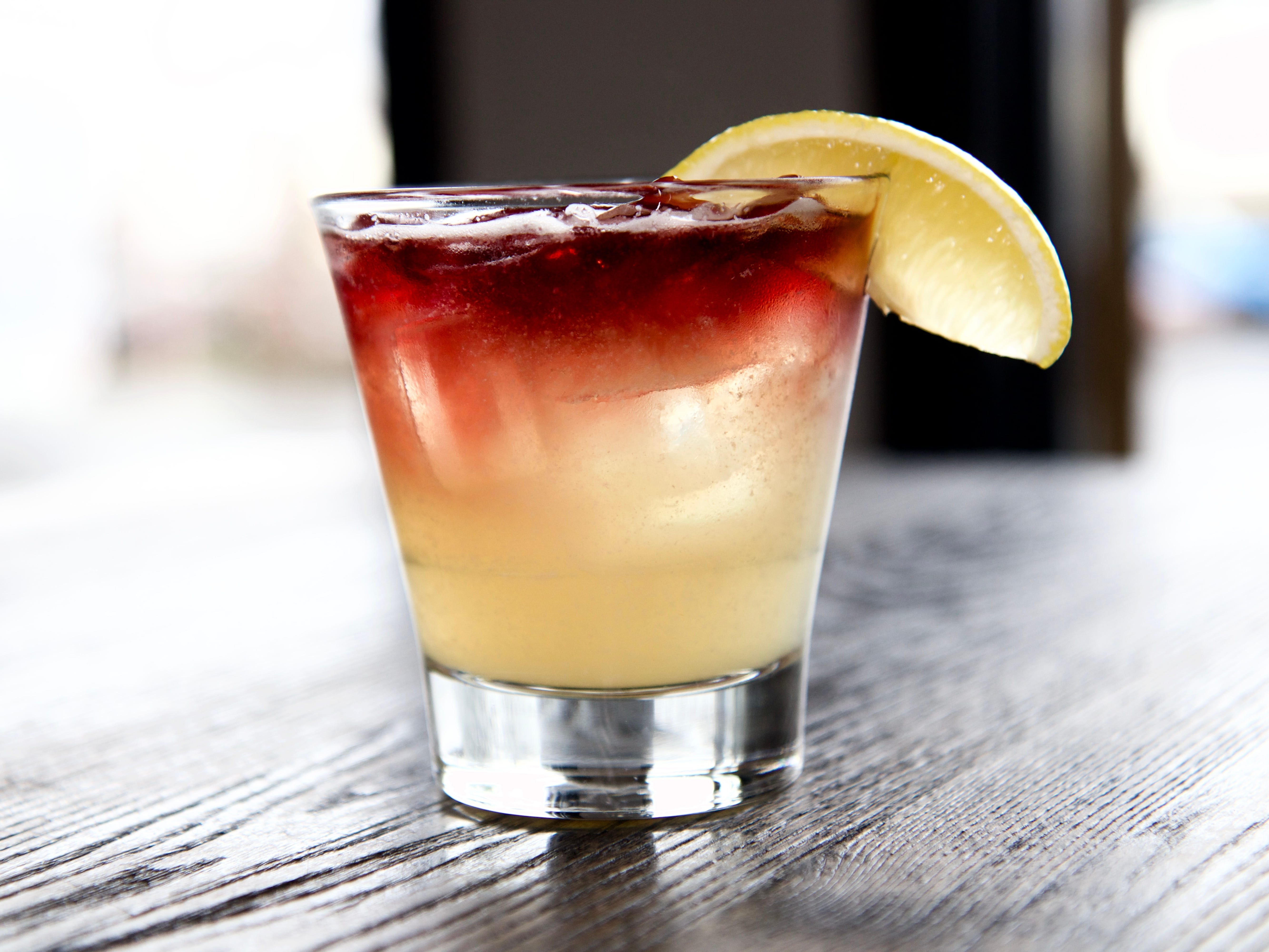 A New York whiskey-sour cocktail in a glass with a lemon slice on the rim.