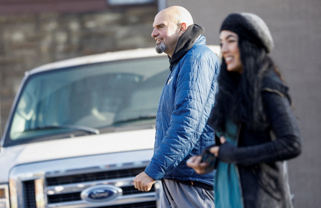 John Fetterman and Gisele Fetterman walking near a vehicle.