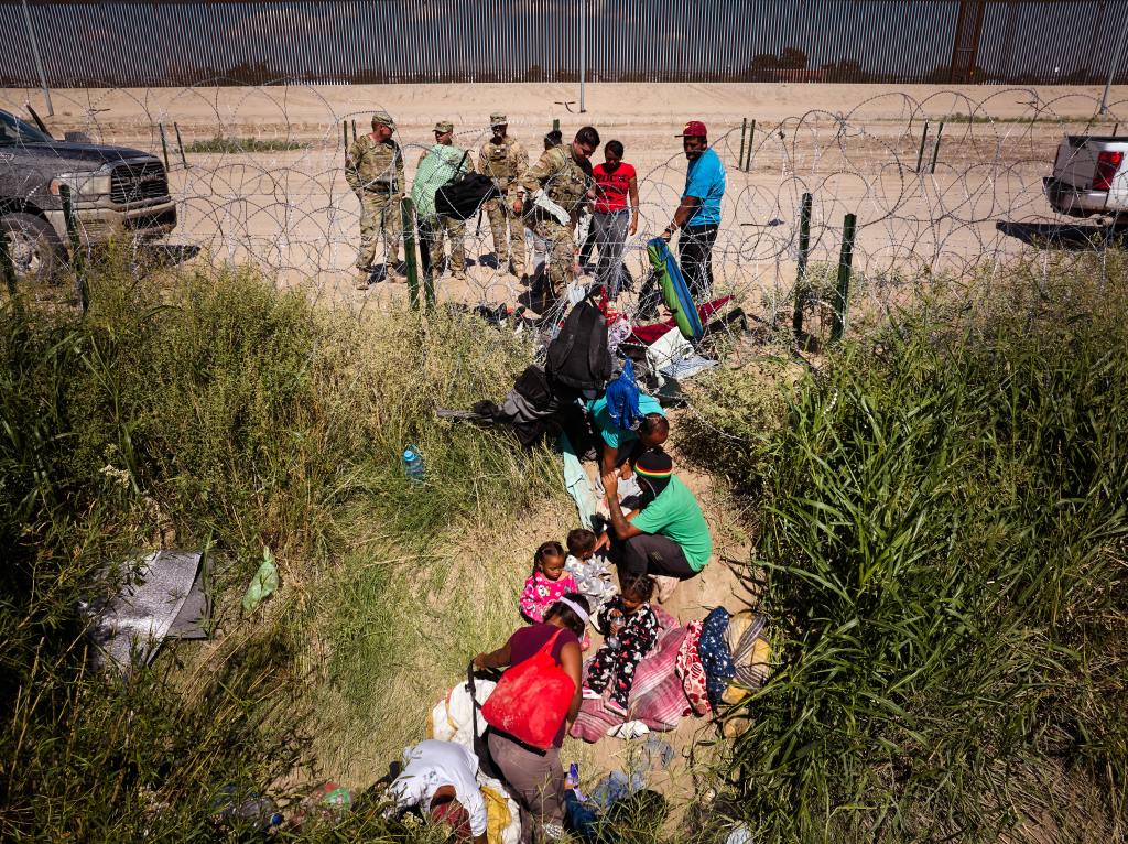 Migrants and Texas National Guard members at the U.S.-Mexico border.