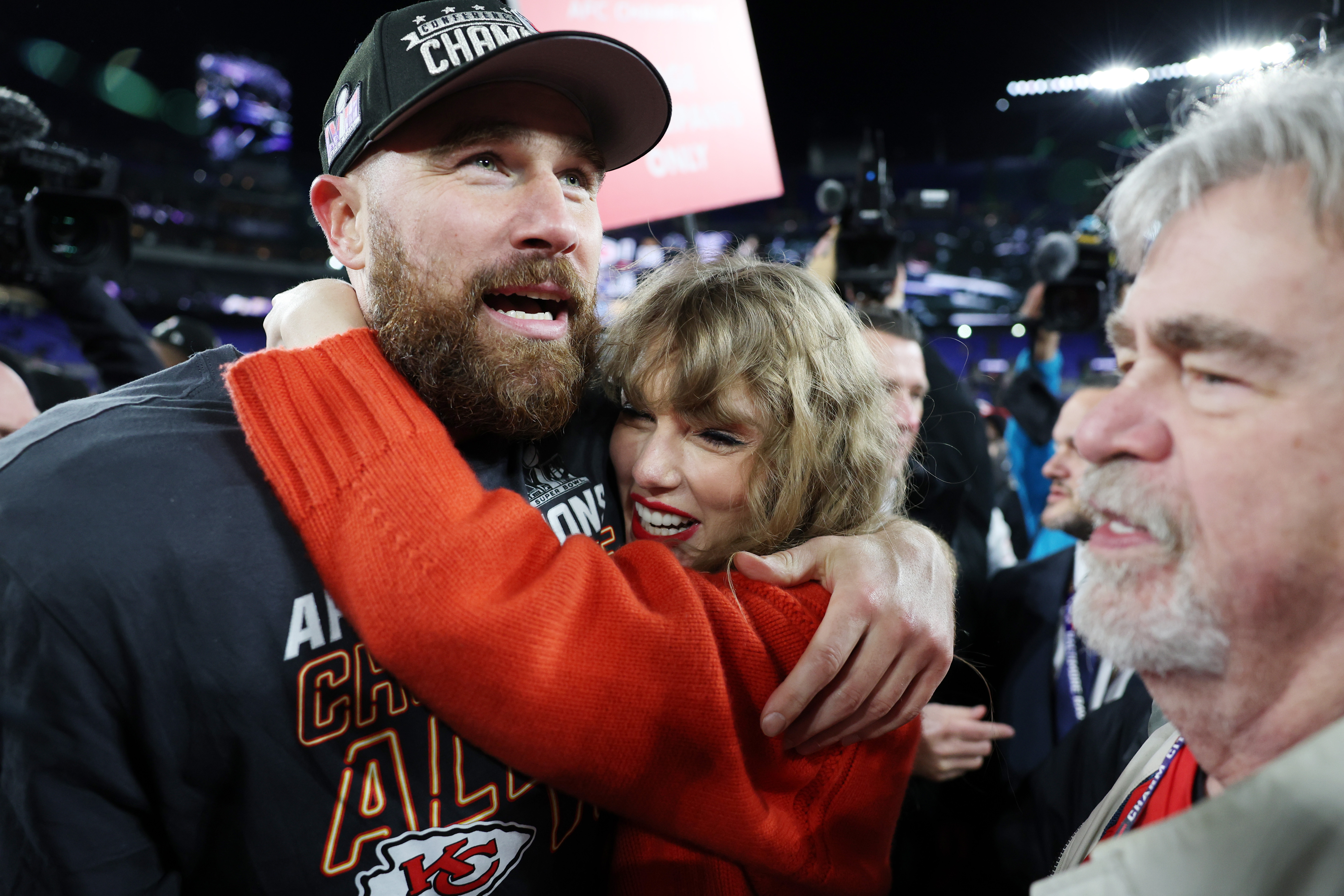 Taylor Swift hugs Travis Kelce on the football field. 