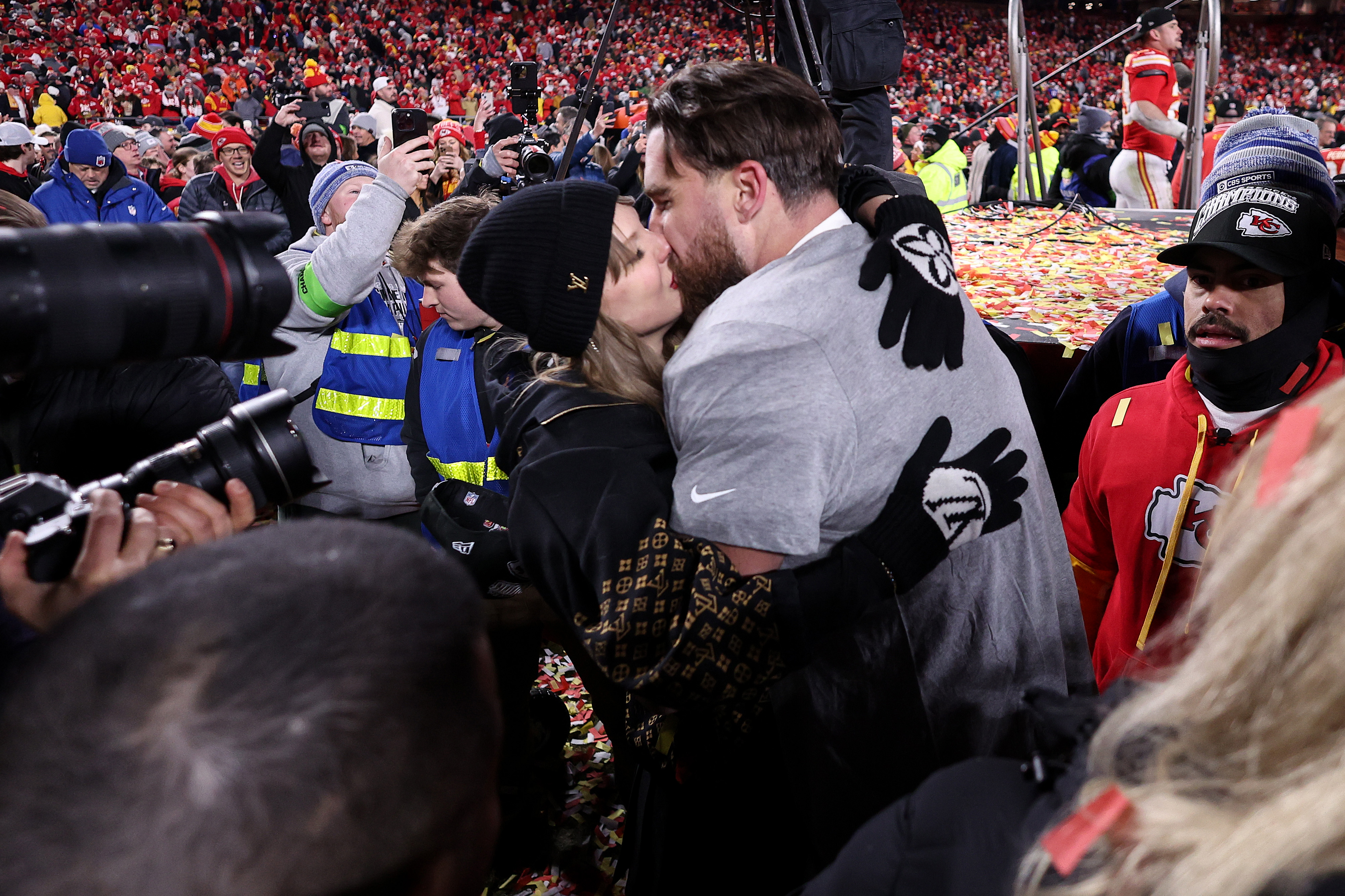 Taylor Swift and Travis Kelce kiss on the football field. 
