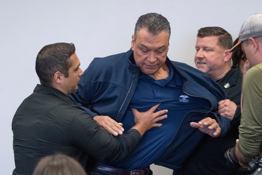 Senator Alex Padilla being escorted from a room.