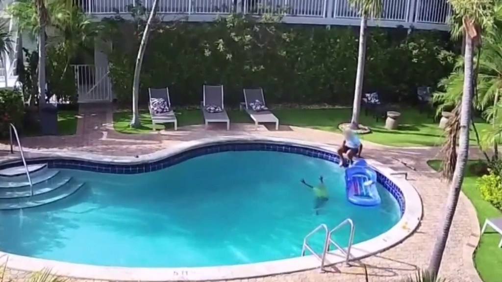 Surveillance footage of a man saving a young boy from a pool.