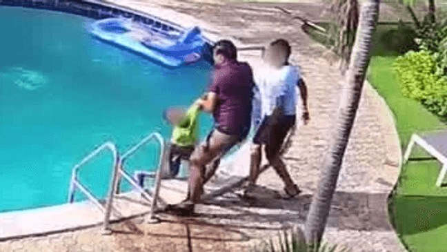 Surveillance video of a man rescuing a child from a pool.