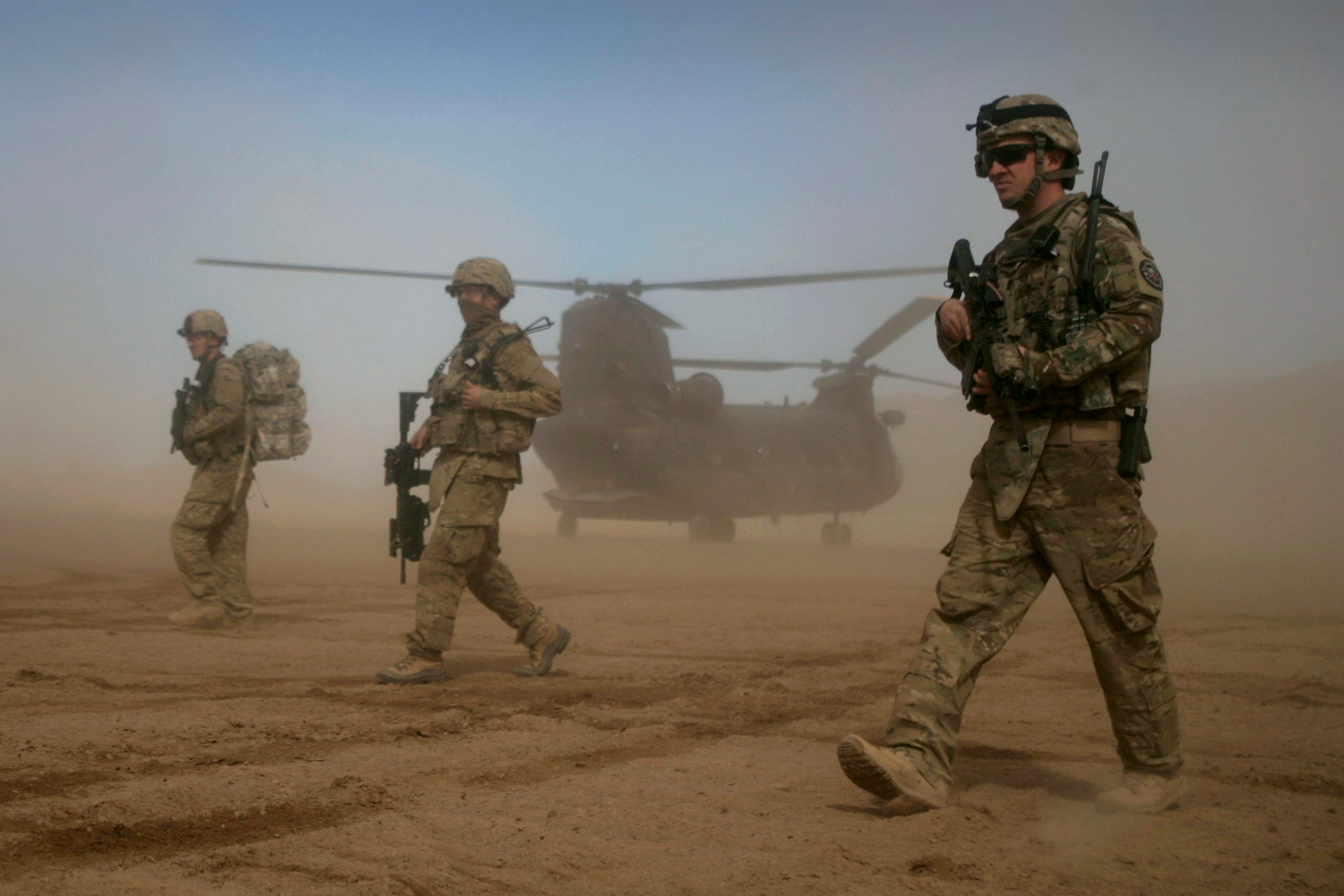 US soldiers, part of the NATO- led International Security Assistance Force (ISAF), walk as a Chinook helicopter is seen on the back ground in Shindand, Herat, west of Kabul, Afghanistan, Saturday, Jan. 28, 2012.