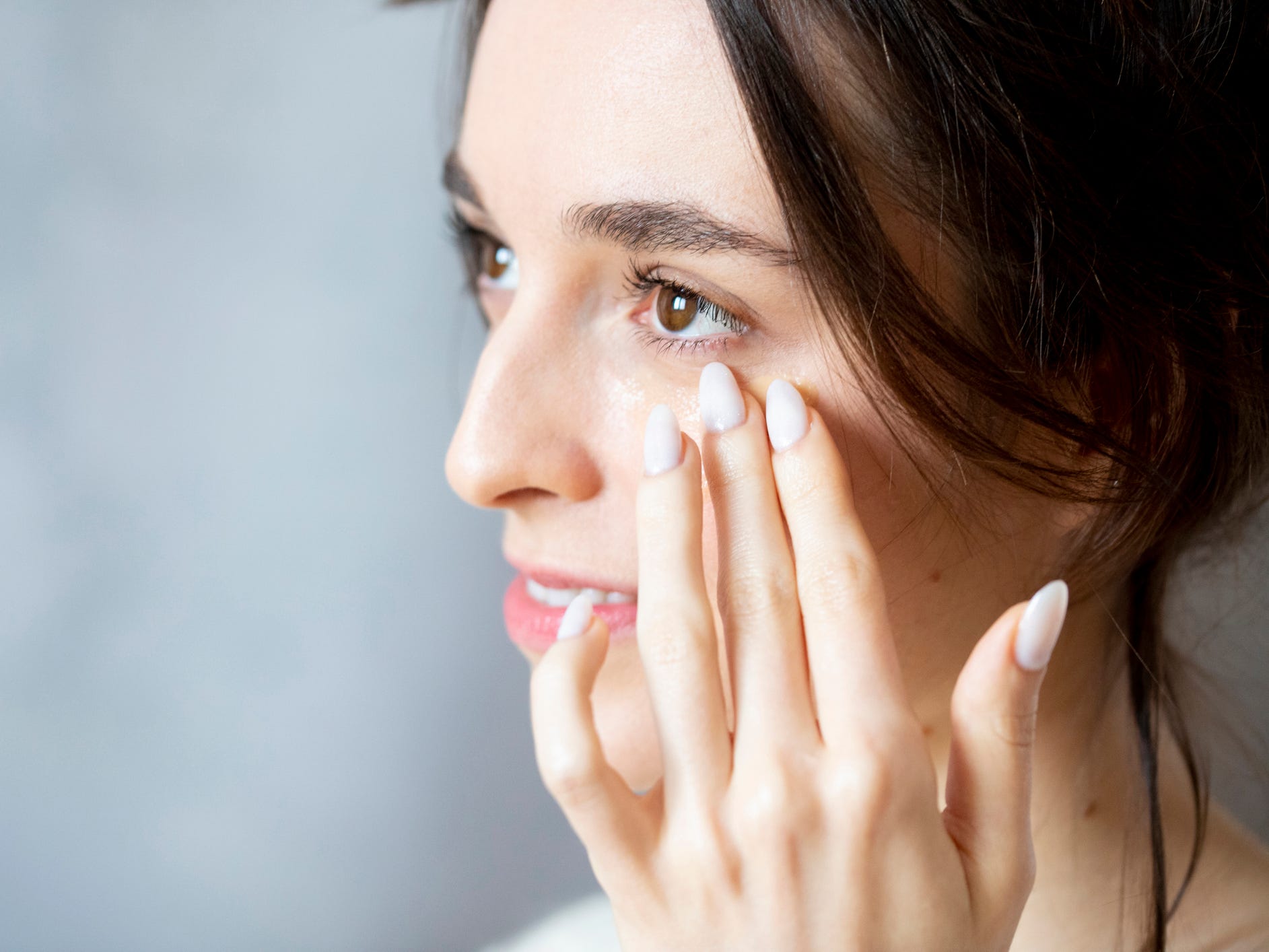 A woman putting on eye cream