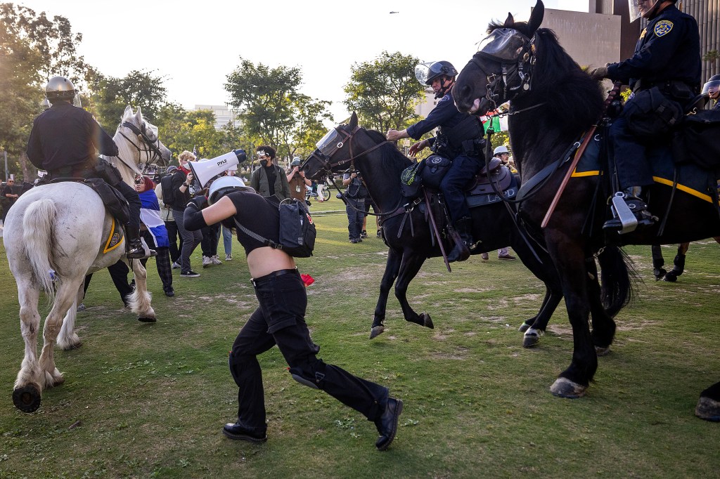 Los Angeles police officers on horseback disperse protesters.