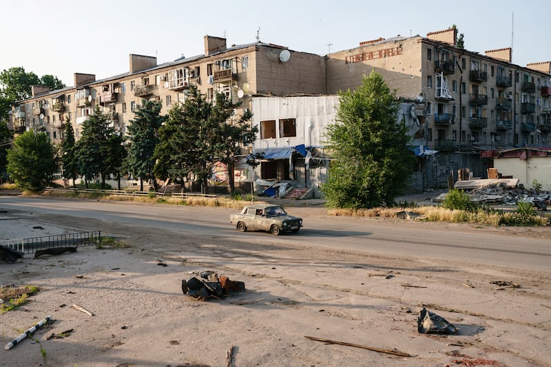 Car is seen on a street next to apartment buildings damaged by Russian military strikes in the frontline town of Kostiantynivka