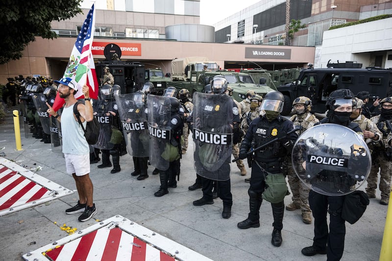 A protester is seen waving a Mexican-American flag outside the Federal Building in Los Angeles.