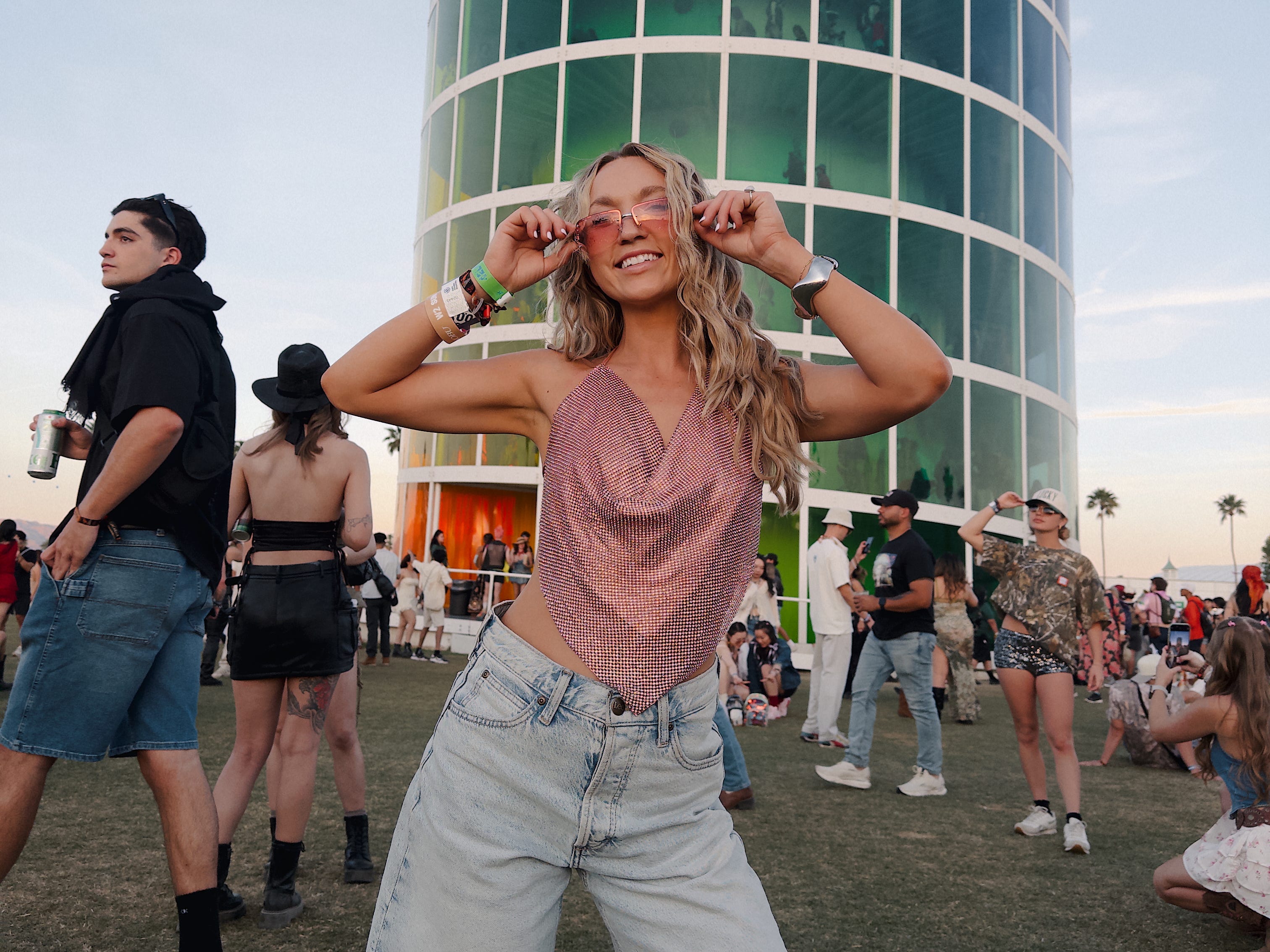 Chloe wears pink glasses as she stands in front of a colorful tower at Coachella Valley Music & Arts Festival.