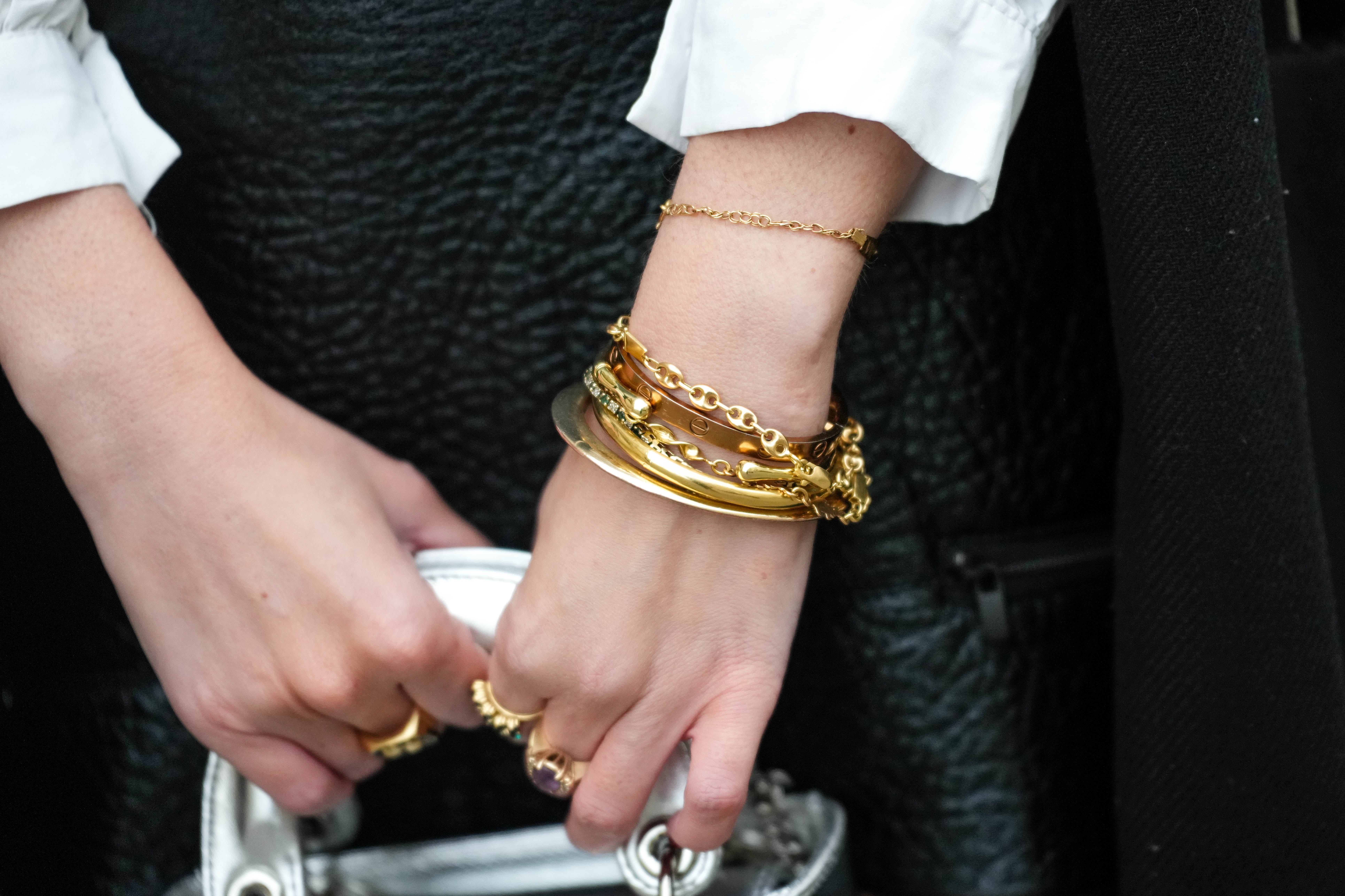 Wrist with various gold bracelets and bangled stacked