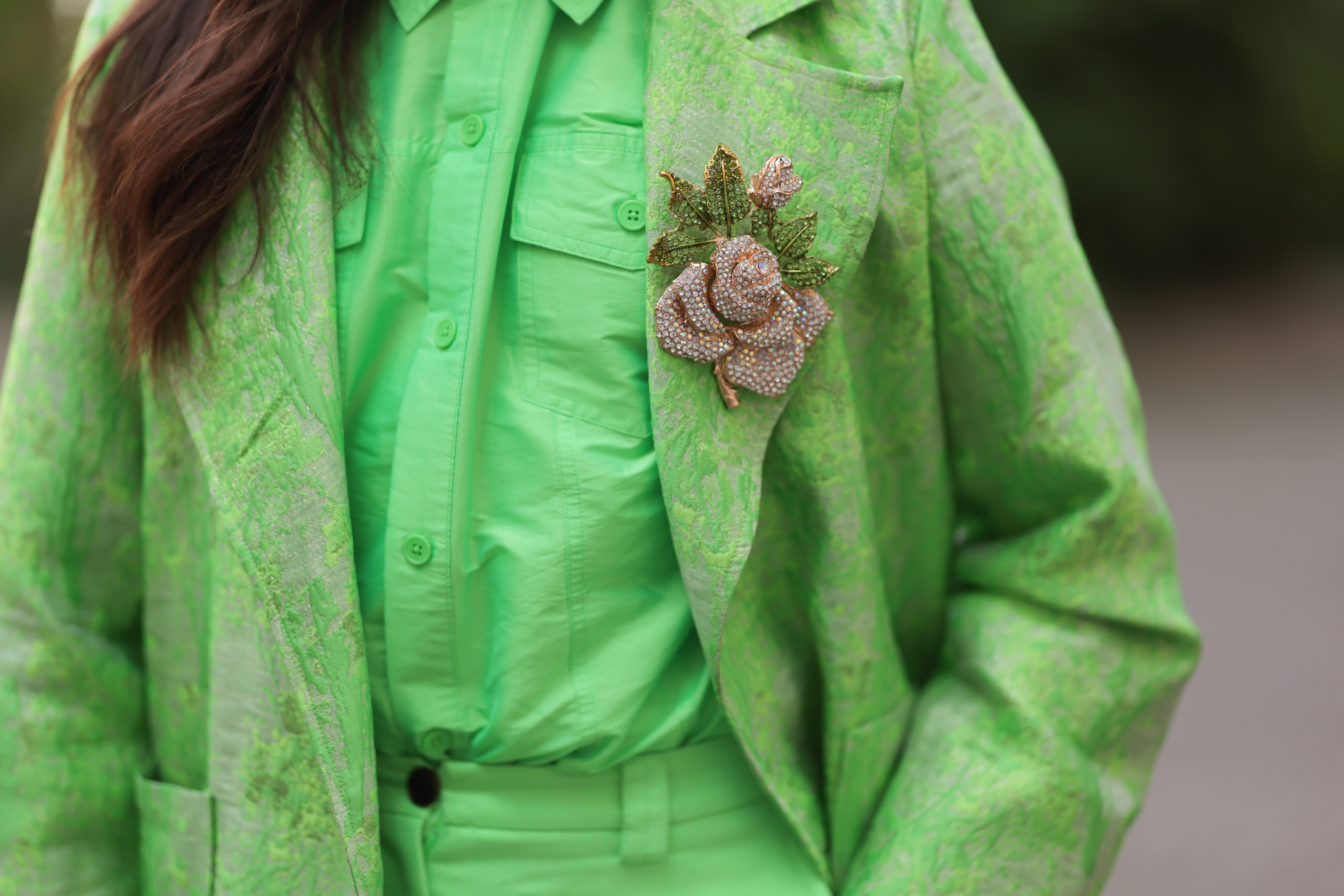 Vibrant green suit with gem-covered floral brooch pinned on lapel