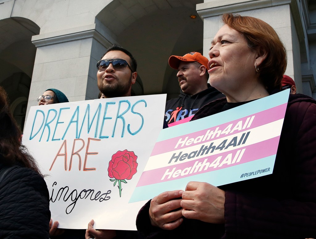 Protestors holding signs advocating for health care for all and for Dreamers.