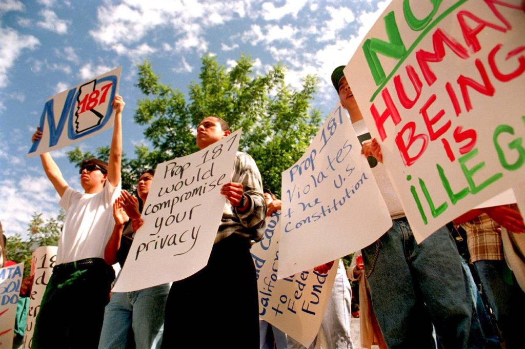 Protestors holding signs against Proposition 187.