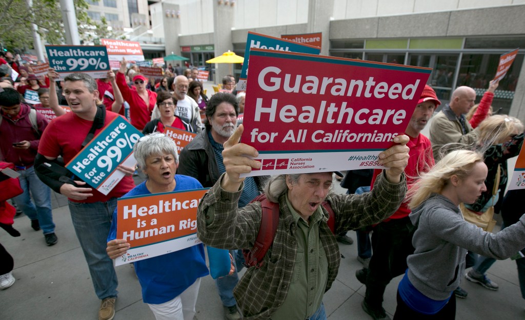 Protestors holding signs advocating for guaranteed healthcare in California.