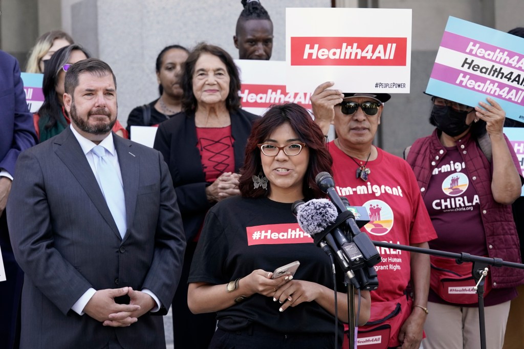 Photo of a woman speaking at a rally in support of healthcare for immigrants.