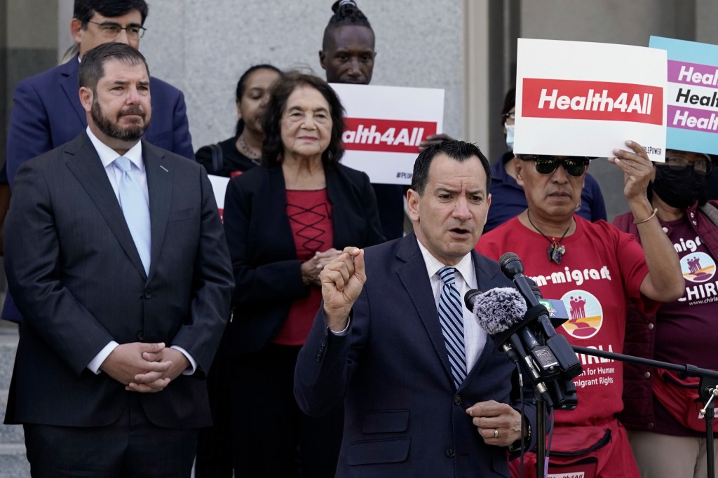 A man speaking at a press conference in support of healthcare for immigrants.