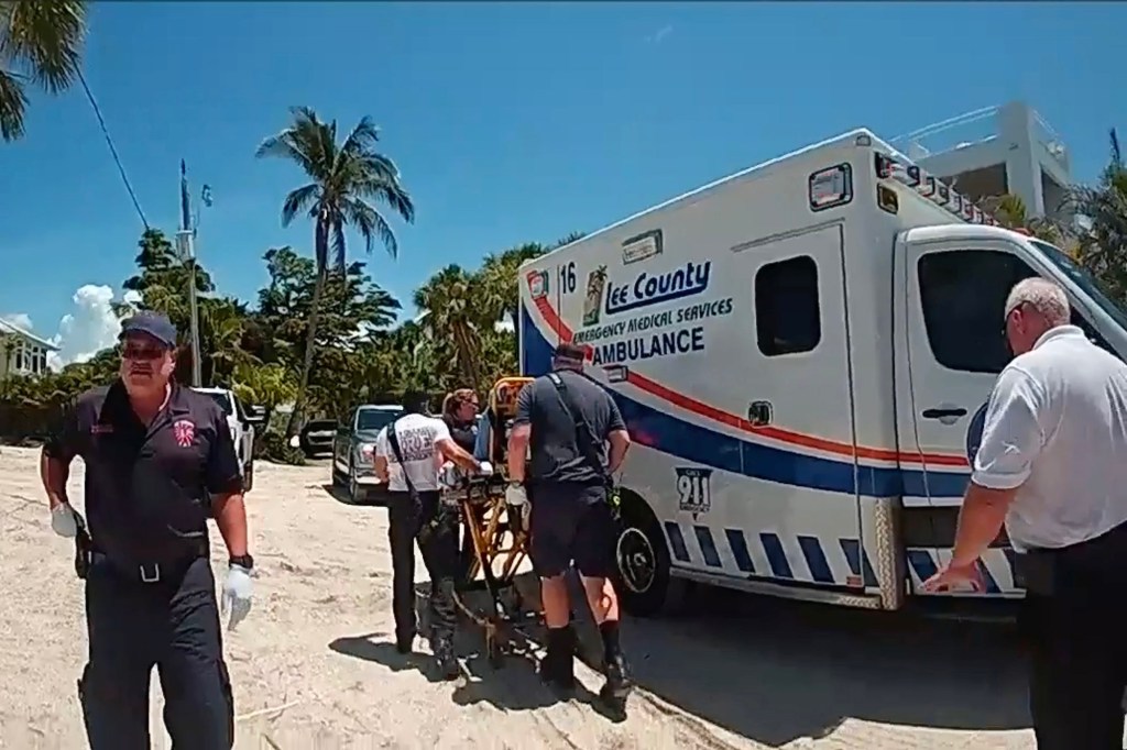 Paramedics loading a patient onto a stretcher next to an ambulance.