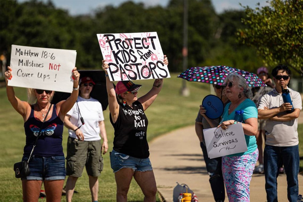 Protestors holding signs advocating for the protection of children from pastors.