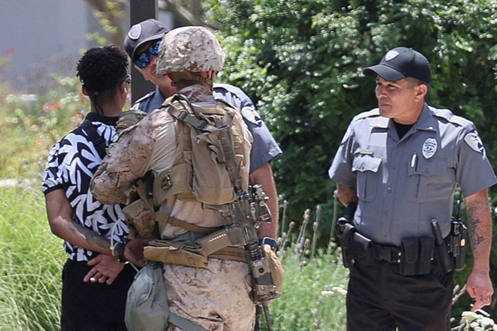 U.S. Marines and police officers interacting with a person in civilian clothing.