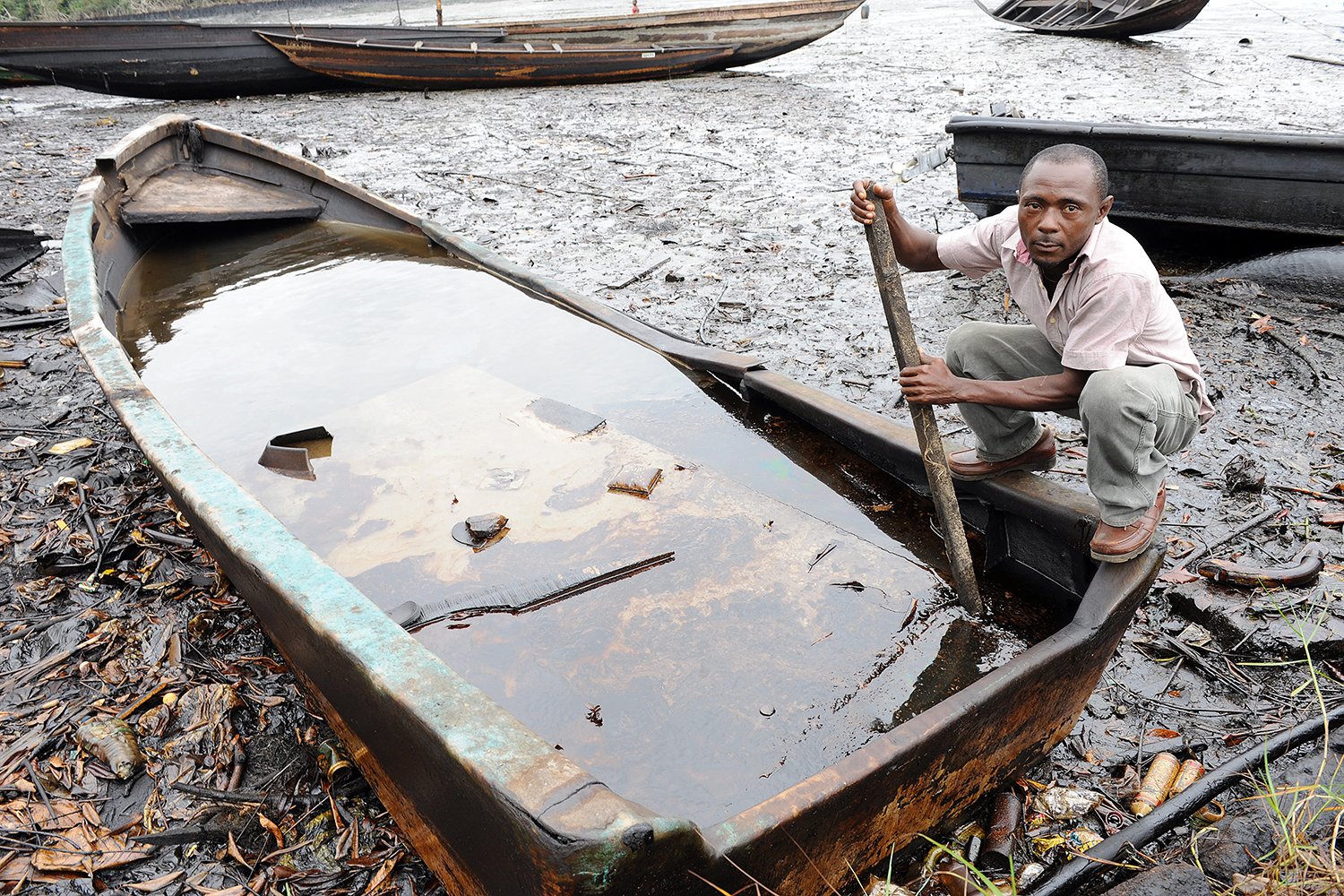 A man tries to separate the crude oil from water in a boat.