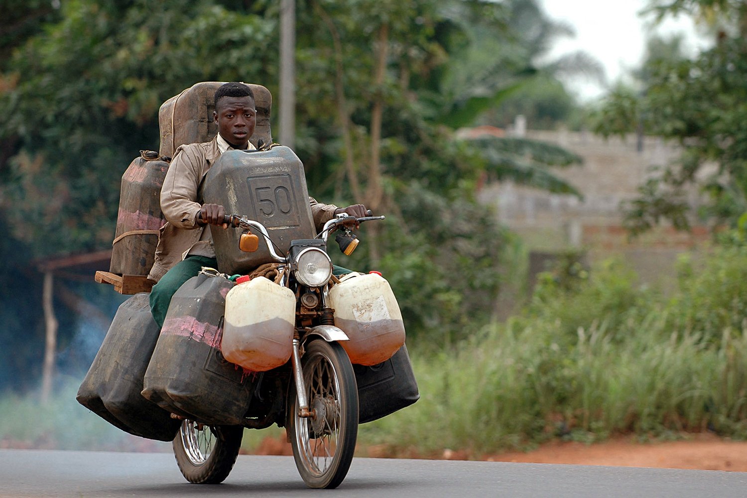 A man carries oil smuggled from Nigeria on his motorcycle.