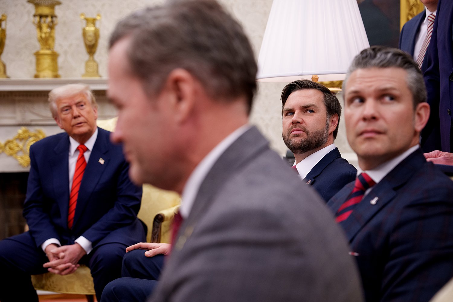 Four men in suits during a meeting in the Oval Office.